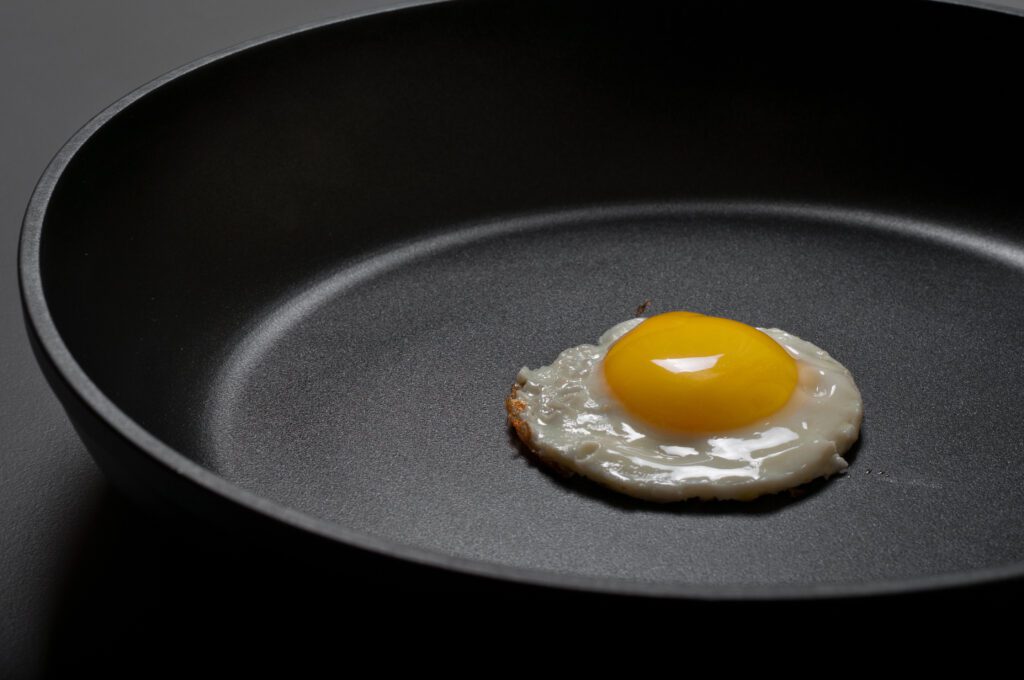 A sunny-side-up egg fries in a non-stick pan.