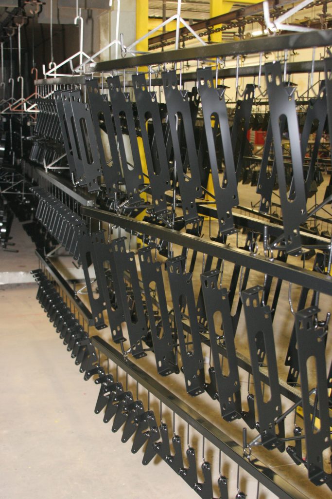 Metal parts hang on a powder coating conveyor line.