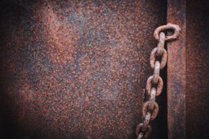 A close-up of a steel ship hull and chain that is rusted from saltwater.