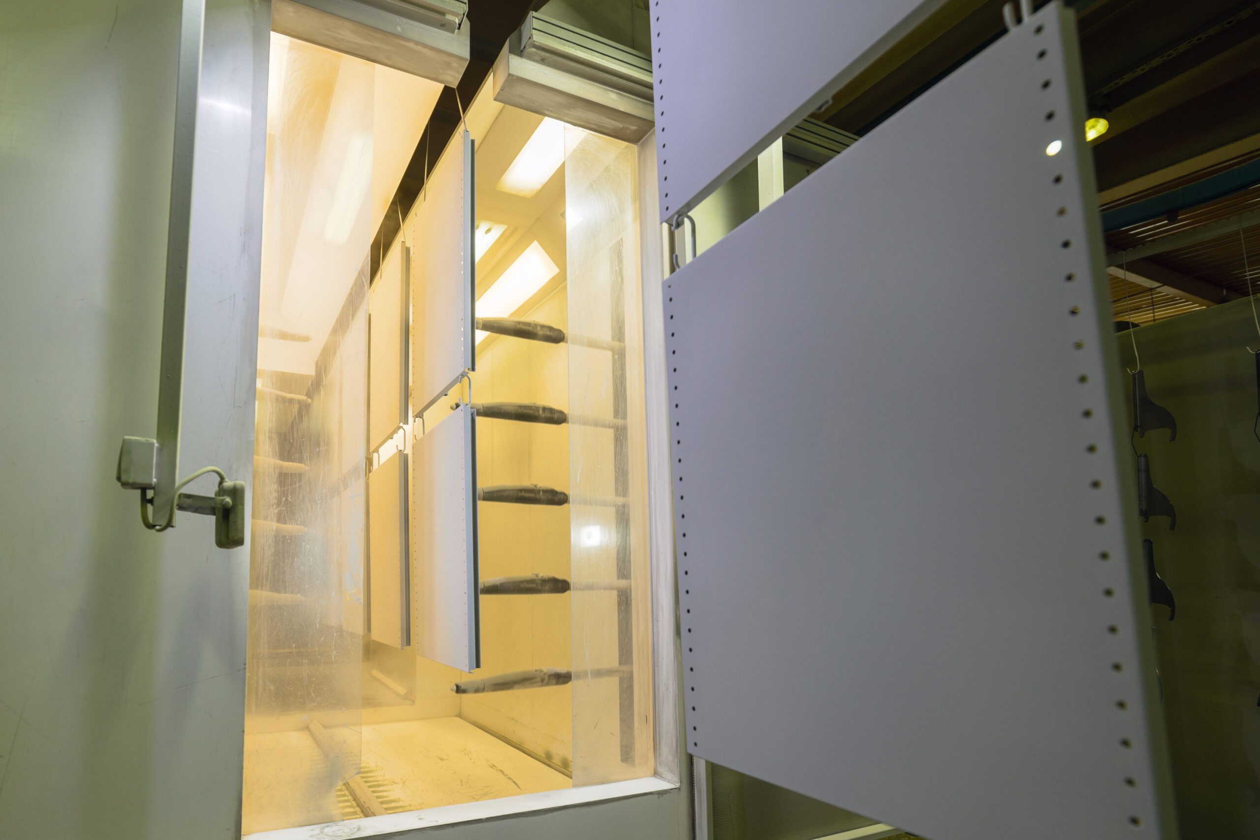 A number of powder-coated metal panels enter a post-dip curing chamber