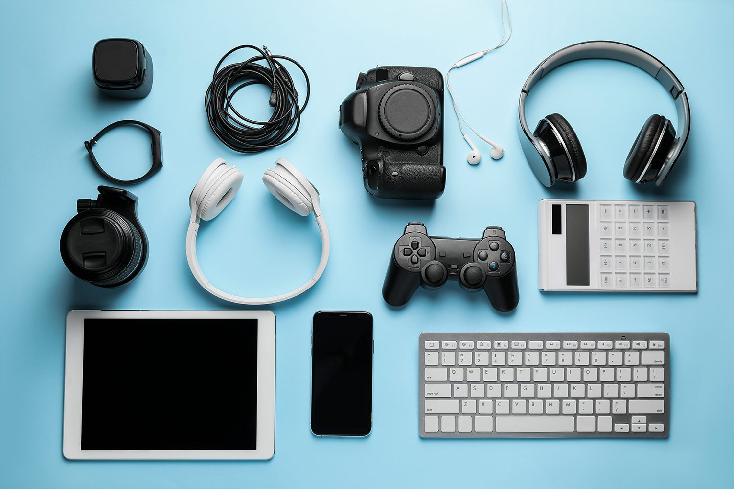 Various electronic items such as a keyboard, tablet, camera, wires, and headphones.