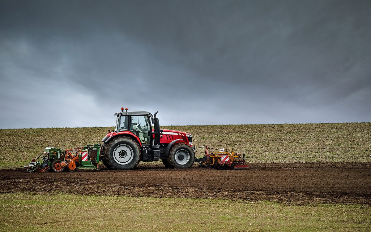 A farmer plowing a field before the storm comes.