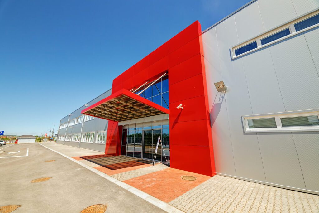 The front of a building with gray walls and a red entrance.