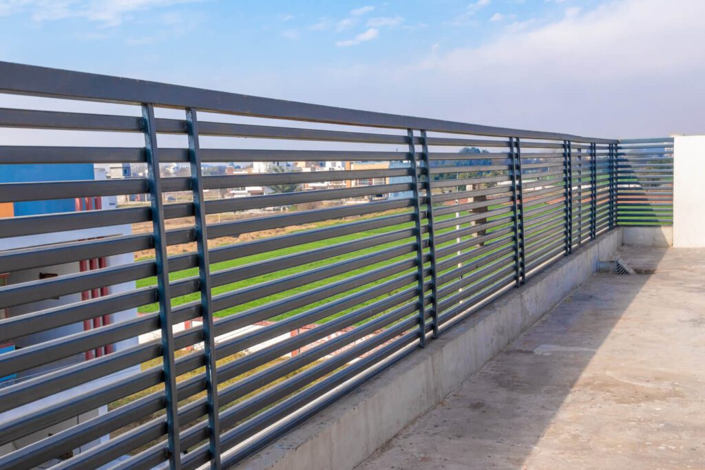 A steel railing on top of a building with a blue-sky background.