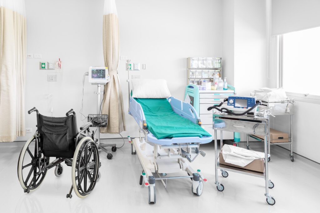 Empty wheelchair parked in a hospital room with medical equipment.