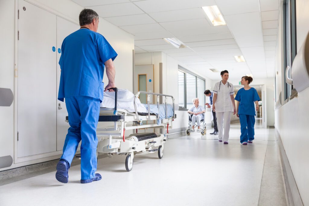 A nurse pushes a patient in a hospital bed down a hall.