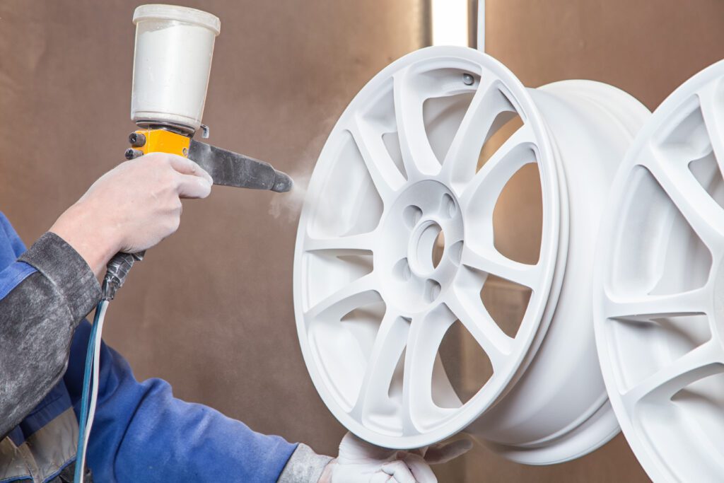 A person powder coating auto wheels.