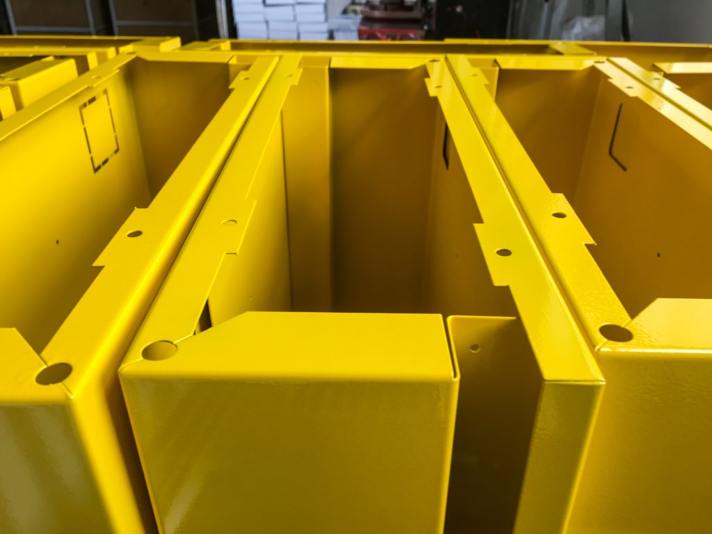A batch of electrical box cases that have been coated with a yellow coating