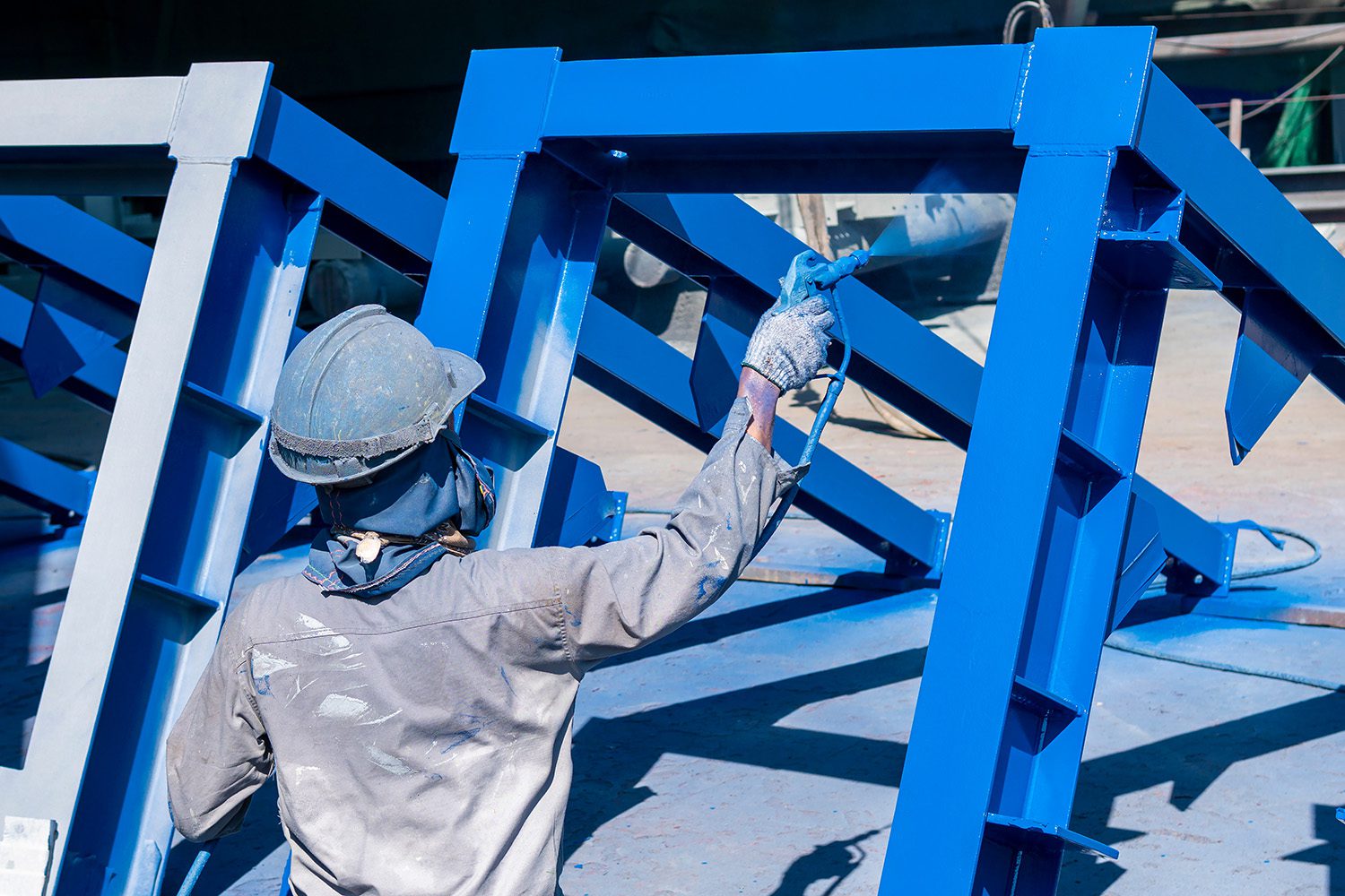 a man spray painting a steel structure