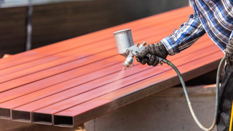 Construction worker spraying paint to steel pipe