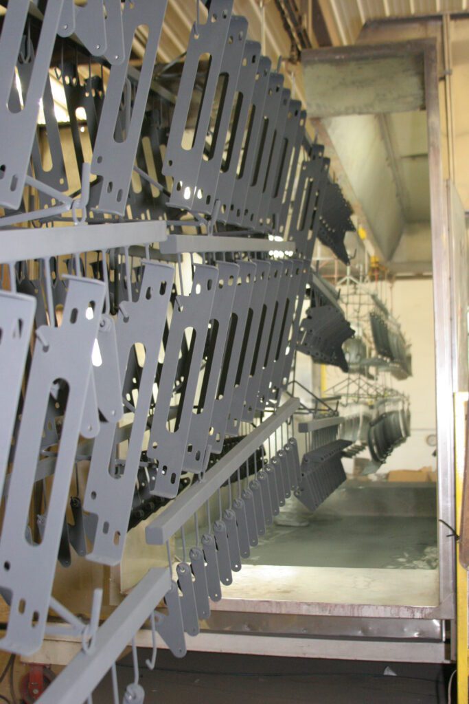 Two rows of hanging metal parts that have been powder-coated in gray.
