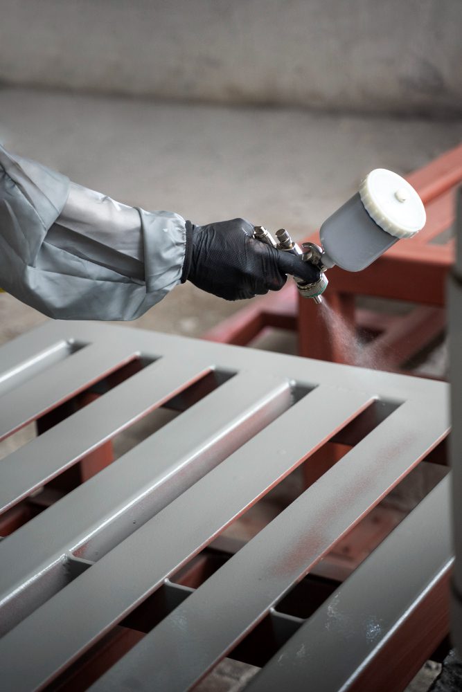 A worker spraying epoxy powder coating.